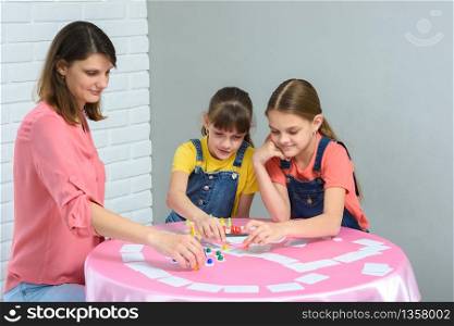 Family plays a board game at a table in a children&rsquo;s room