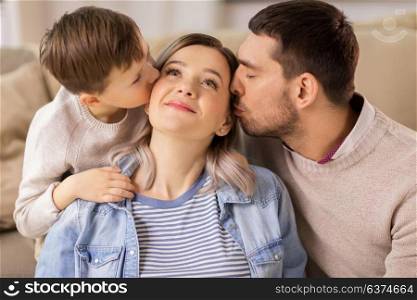 family, portrait and people concept - happy little son and father kissing mother at home. happy family portrait at home