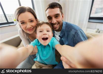 family, portrait and people concept - happy little son with mother and father taking selfie at home. happy family taking selfie at home