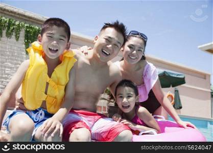 Family portrait, mother, father, daughter, and son, smiling by the pool