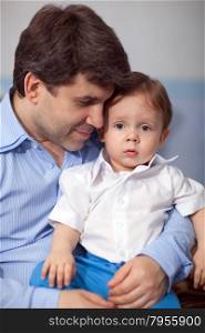 Family portrait of a young father holding lovely little son in his arms. Dad looking at the boy. Happy fatherhood
