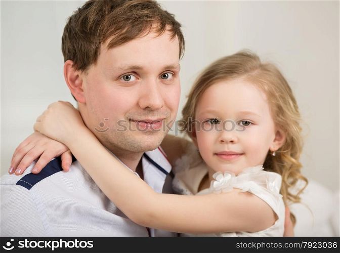 Family portrait of little daughter embracing neck of happy beloved father. Happy father with his little princess