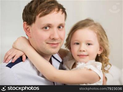 Family portrait of little daughter embracing neck of happy beloved father. Happy father with his little princess