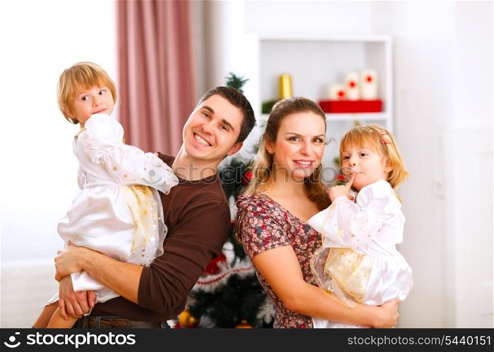 Family portrait of mother father and twins daughter near Christmas tree&#xA;