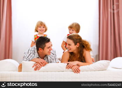 Family portrait of mother father and twins daughters on bed&#xA;