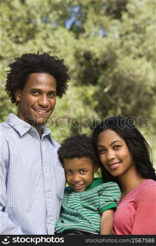 Family portrait of parents and young son smiling.
