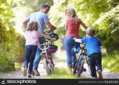 Family Pushing Bikes Along Country Track