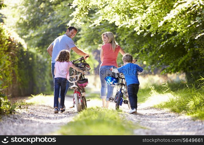 Family Pushing Bikes Along Country Track