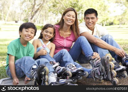 Family Putting On In Line Skates In Park