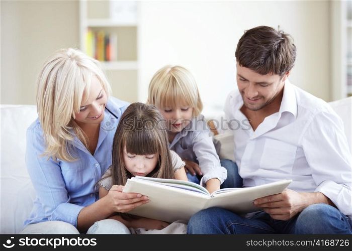 Family reading a book at home on the couch