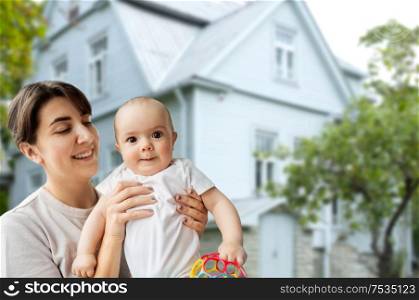 family, real estate and home concept - happy smiling young mother holding little baby daughter over house background. happy young mother holding little baby daughter