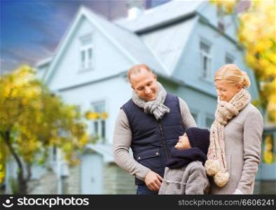 family, real estate and people concept - happy mother, father and son over living house background outdoors in autumn. happy family over living house in autumn