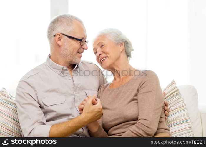 family, relations, age and people concept - happy senior couple hugging on sofa at home