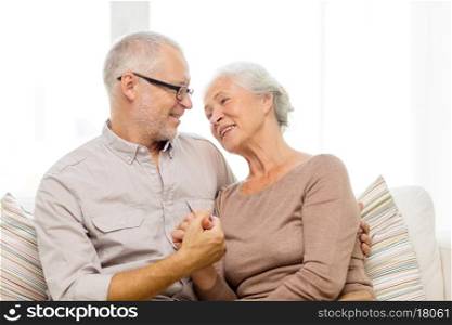family, relations, age and people concept - happy senior couple hugging on sofa at home