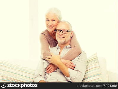 family, relations, age and people concept - happy senior couple hugging on sofa at home