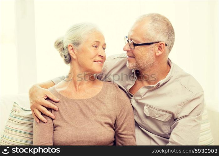 family, relations, age and people concept - happy senior couple hugging on sofa at home