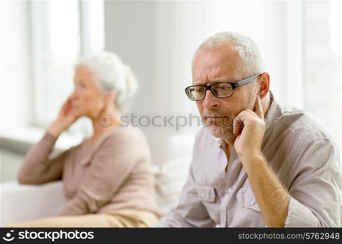 family, relations, age and people concept - senior couple sitting on sofa at home