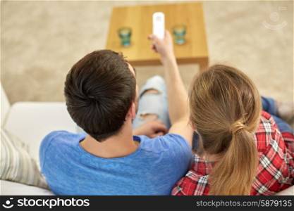 family, relations and leisure concept - close up of couple with remote control watching tv together at home