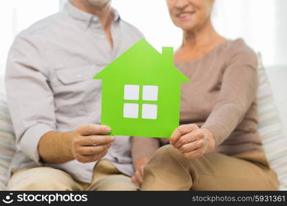 family, relations, real estate, age and people concept - close up of happy senior couple with green paper house cutout at home