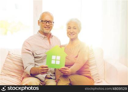 family, relations, real estate, age and people concept - happy senior couple with green paper house cutout at home