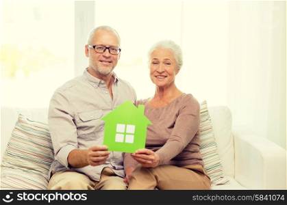 family, relations, real estate, age and people concept - happy senior couple with green paper house cutout at home