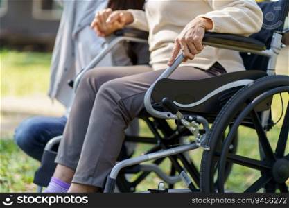 Family relationship Asian senior woman in wheelchair with happy daughter holding caregiver for a hand while spending time together.