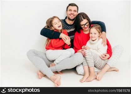 Family relationship concept. Cute cheerful little small girl have fun and enjoy spare time with their parents. Happy male father embraces his wife and daughters, feels delighted, isolated on white