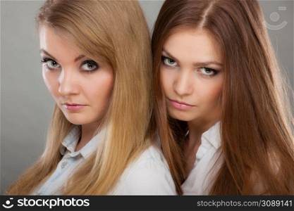Family relationships, friendship concept. Two beautiful women sisters, blonde and brunette with windblown hair posing charmingly.. Two beautiful women, blonde and brunette posing