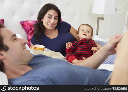 Family Relaxing In Bed With Coffee And Newspaper