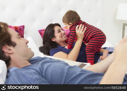 Family Relaxing In Bed With Young Son