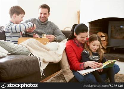 Family Relaxing Indoors Playing Chess And Reading Book