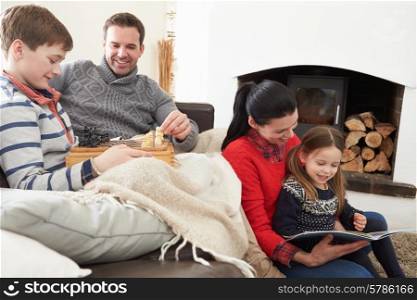 Family Relaxing Indoors Playing Chess And Reading Book