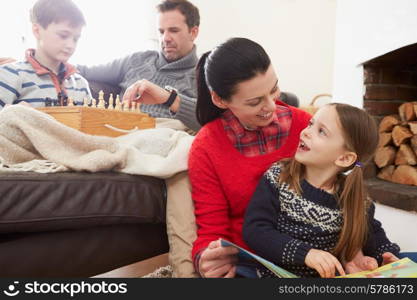 Family Relaxing Indoors Playing Chess And Reading Book