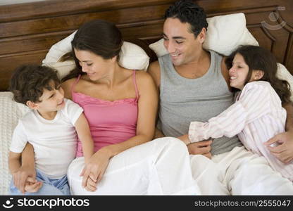 Family relaxing on bed in bedroom smiling (selective focus)