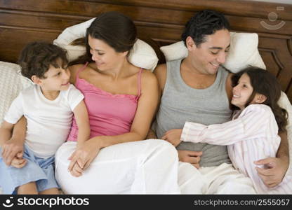 Family relaxing on bed in bedroom smiling (selective focus)