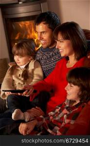 Family Relaxing Watching TV By Cosy Log Fire