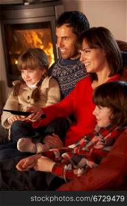Family Relaxing Watching TV By Cosy Log Fire