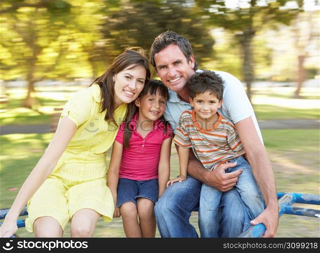 Family Riding On Roundabout In Park