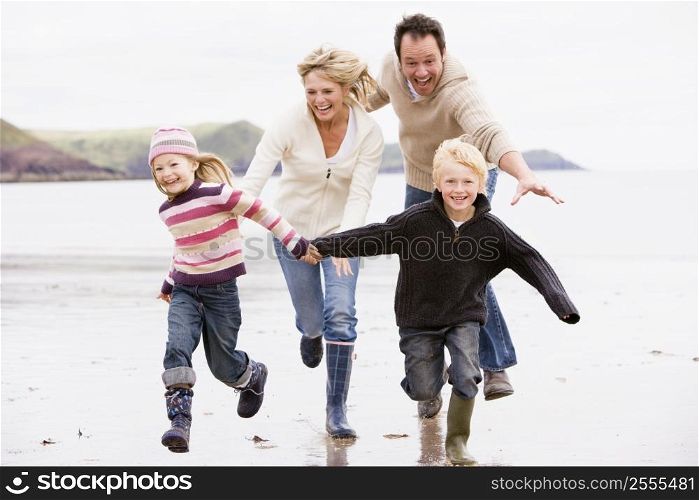 Family running on beach holding hands smiling