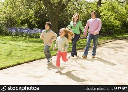 Family running on path holding hands smiling