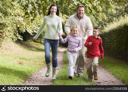 Family running on path outdoors smiling (selective focus)