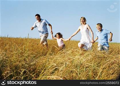 Family running outdoors holding hands smiling