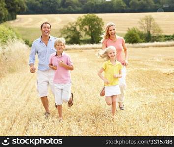 Family Running Together Through Summer Harvested Field