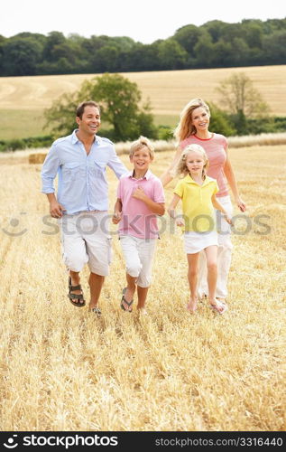 Family Running Together Through Summer Harvested Field