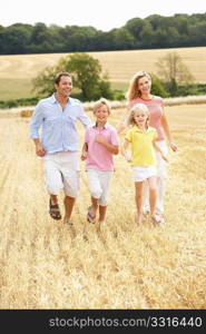 Family Running Together Through Summer Harvested Field