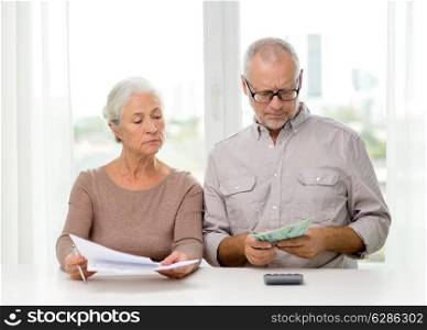 family, savings, age and people concept - senior couple with papers, money and calculator at home