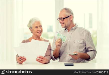 family, savings, age and people concept - smiling senior couple with papers, money and calculator at home