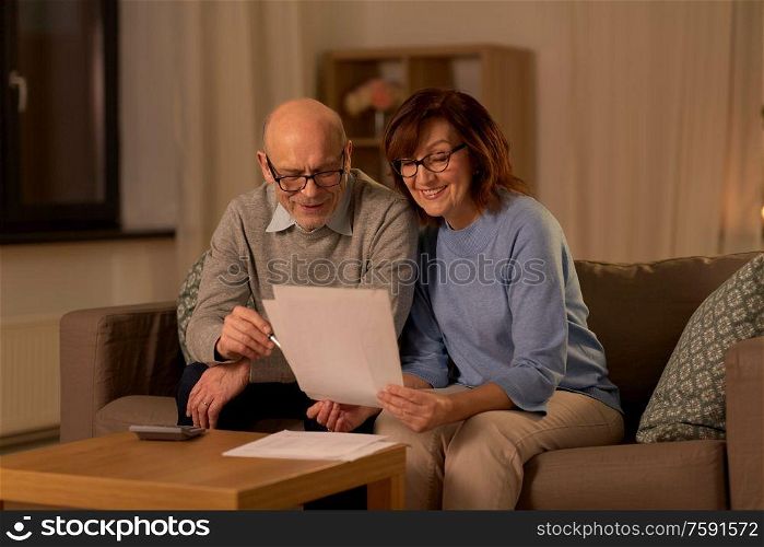 family, savings and people concept - smiling senior couple with papers and calculator at home. senior couple with papers and calculator at home