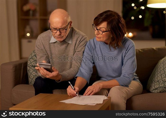 family, savings and people concept - smiling senior couple with papers and calculator at home. senior couple with papers and calculator at home
