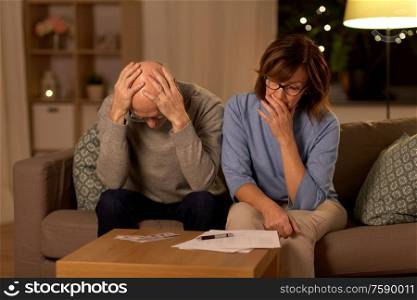 family, savings and people concept - unhappy senior couple with bills and money at home. unhappy senior couple with bills and money at home